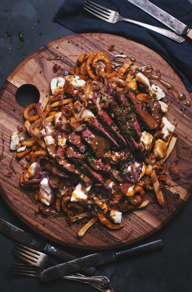 Deluxe poutine with beef ribeye steak, bacon and beer caramelized onions