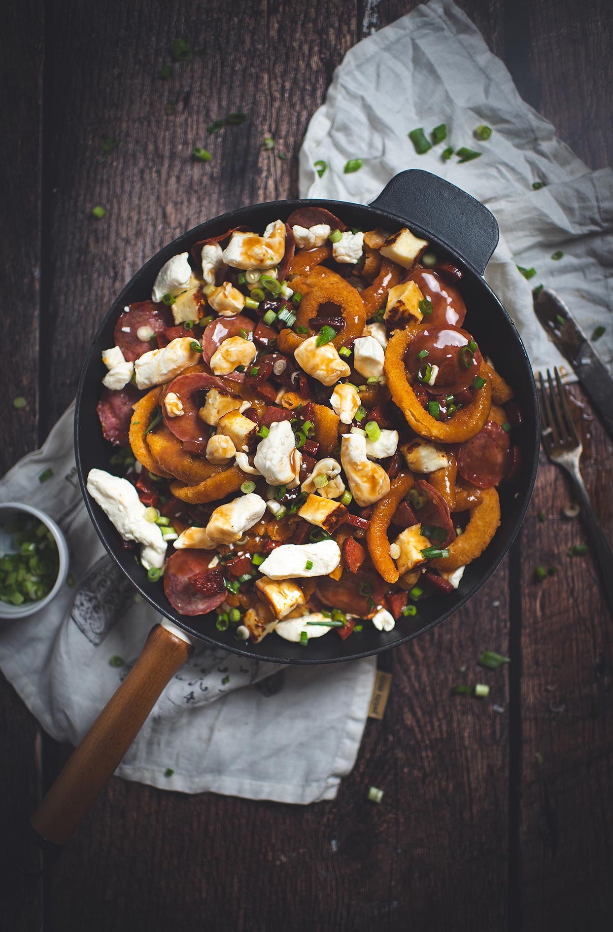 Poutine à la rondelle d’oignon avec chorizo, salami et haloumi