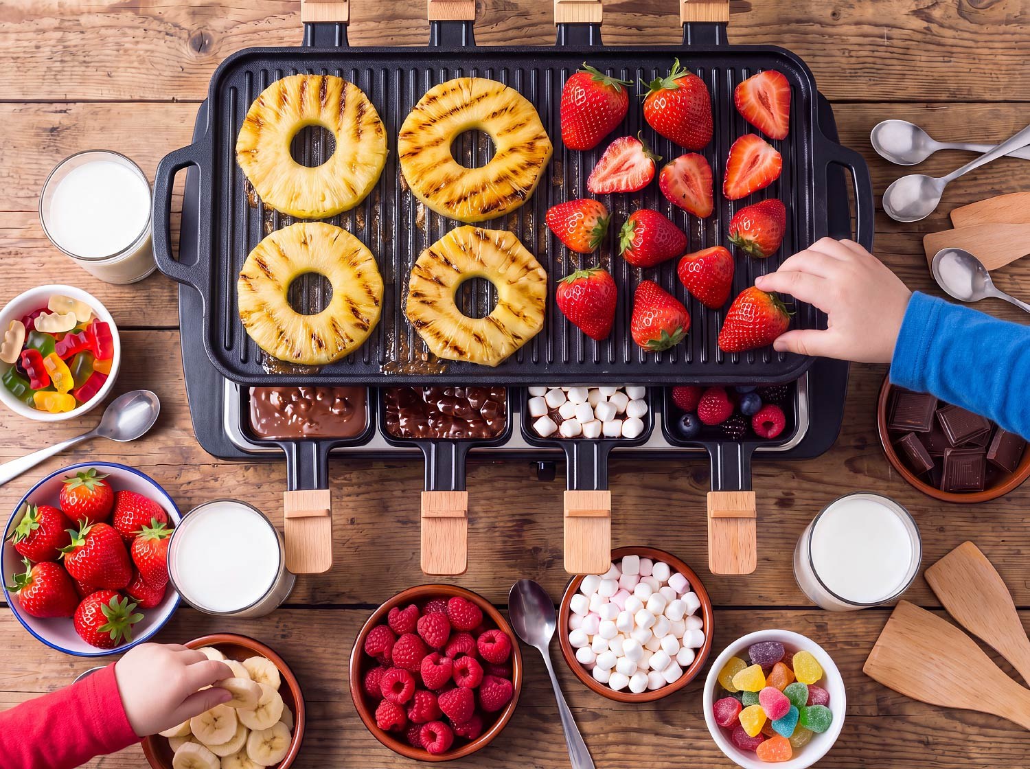 Raclette dessert : chocolat fondu et guimauves dans les poêlons, ananas et fraises grillés sur la plaque